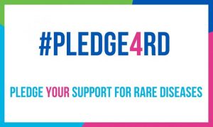 Schild in bunter Schrift. Das Bild zeigt den Hashtag pledge 4 RD und darunter den Schriftzug Pledge your support for rare diseases