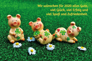 Drei Schweinchen Figuren sitzen und liegen auf einer satt grünen Wiese, davor vier Gänseblümchen. Im Bild steht der Text Wir wünschen für 2020 alles Gute, viel Glück, viel Erfolg und Spaß und Zufriedenheit.